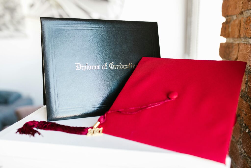 pexels photo 7713436 7713436 Close-up of a vibrant red graduation cap and diploma, symbolizing achievement.